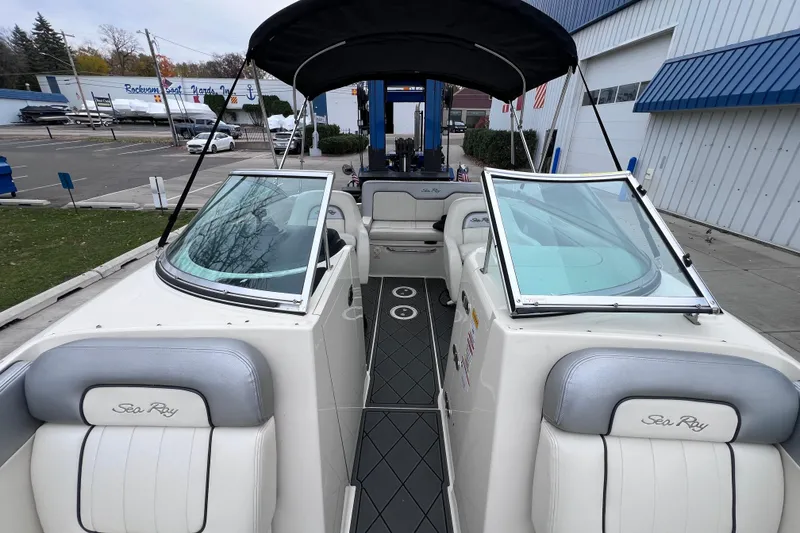 Slide: The Image of 2010 Sea Ray 220 Sundeck boat with open cockpit and seating, docked near a marina. - 28