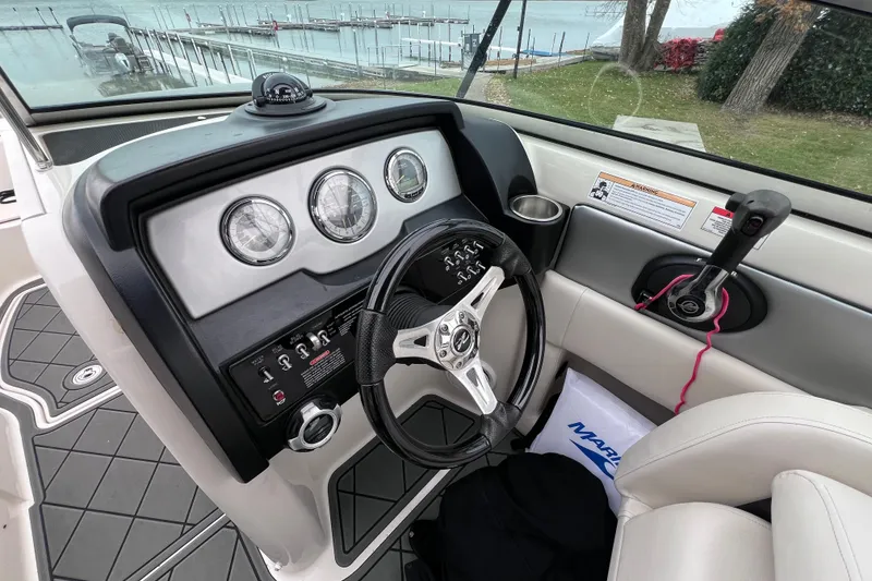 Slide: The Image of 2010 Sea Ray 220 Sundeck dashboard with steering wheel and controls, overlooking a marina. - 29