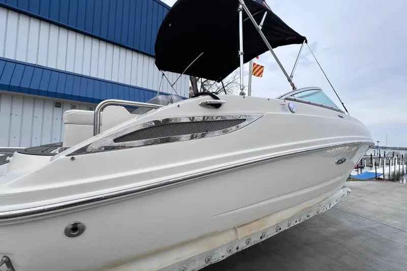 Slide: The Image of 2010 Sea Ray 220 Sundeck boat with black canopy, docked near a blue building. - 3