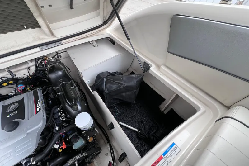 Slide: The Image of Open engine compartment of 2010 Sea Ray 220 Sundeck boat, showcasing engine and storage area. - 45