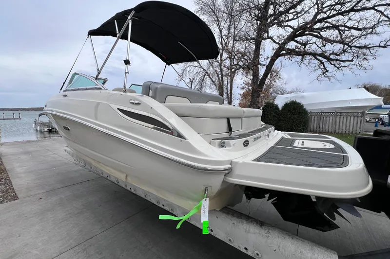 Slide: The Image of 2010 Sea Ray 220 Sundeck boat on trailer near lake, with canopy and seating. - 6