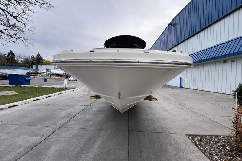 Slide: The Image of 2010 Sea Ray 220 Sundeck boat on a concrete driveway near a blue building. - 7