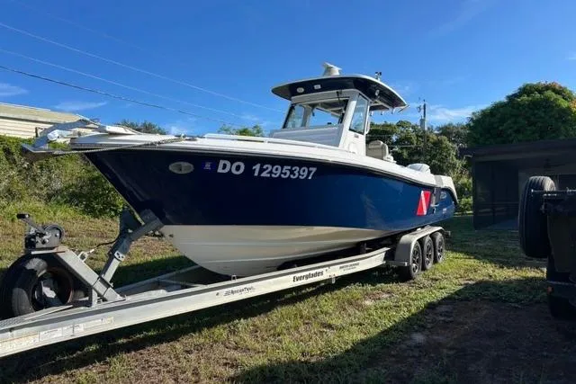 The Image of 2019 Everglades 290 Center Console boat on trailer, parked outdoors under clear blue sky. - 1