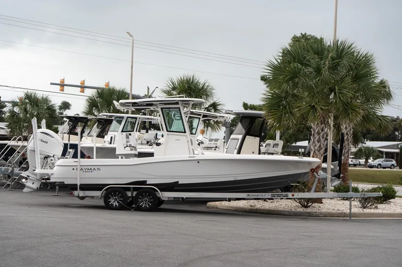 The Image of 2026 Caymas 26 HB boat on trailer, parked near palm trees. - 1