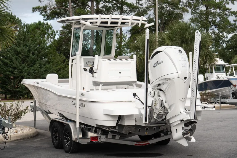 Slide: The Image of 2026 Caymas 26 HB boat with Yamaha engine, parked on a trailer, surrounded by trees. - 6