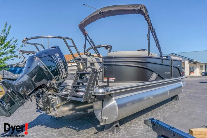 Slide: The Image of 2026 Crest Conquest 210 SLC pontoon boat with Suzuki outboard motor, parked outdoors. - 4