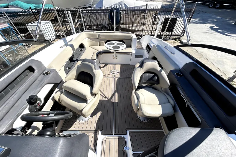 Slide: The Image of 2018 Rinker Q5 OB boat interior with seating and steering wheel, docked outdoors. - 12