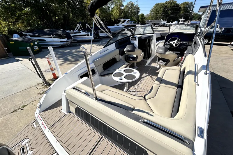 Slide: The Image of 2018 Rinker Q5 OB boat interior with seating and steering wheel, docked outdoors. - 13