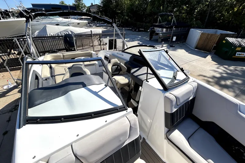 Slide: The Image of 2018 Rinker Q5 OB boat interior with seating and windshield, docked outdoors. - 18