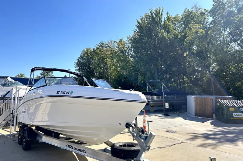 Slide: The Image of 2018 Rinker Q5 OB boat on trailer, parked outdoors under clear blue sky. - 3