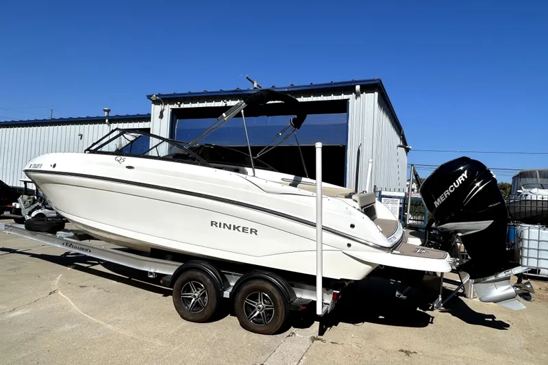 Slide: The Image of 2018 Rinker Q5 OB boat on trailer with Mercury outboard motor, parked outside a warehouse. - 4