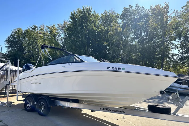 Slide: The Image of 2018 Rinker Q5 OB boat on trailer, surrounded by trees, under clear blue sky. - 6