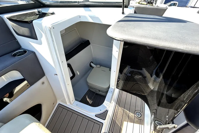 Slide: The Image of 2018 Rinker Q5 OB boat interior with compact toilet and seating area. - 8