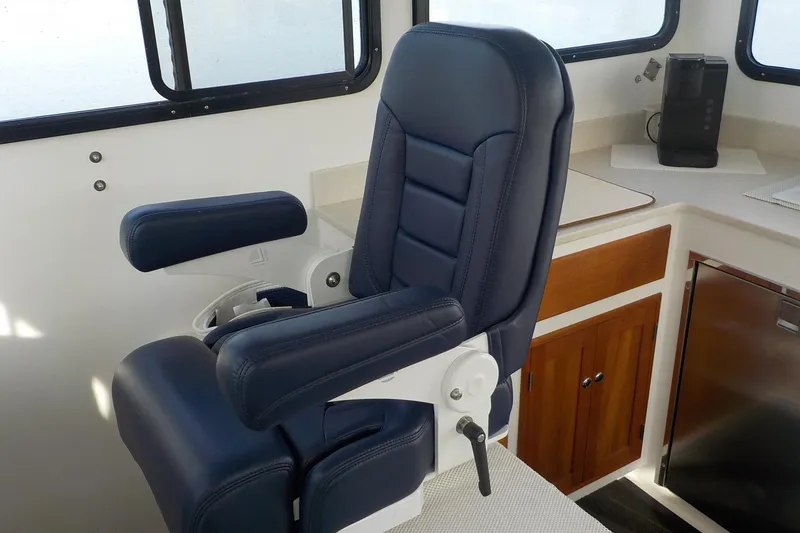 Slide: The Image of Captain's chair in 2008 Calvin Beal Downeast boat interior, featuring blue upholstery and wooden cabinetry. - 20