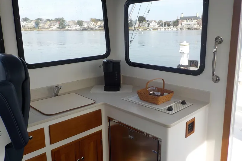 Slide: The Image of 2008 Calvin Beal Downeast boat interior with kitchenette, window view of waterfront homes. - 23