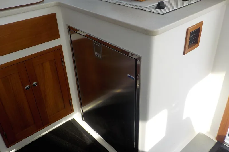 Slide: The Image of 2008 Calvin Beal Downeast boat interior with stainless steel fridge and wooden cabinets. - 25