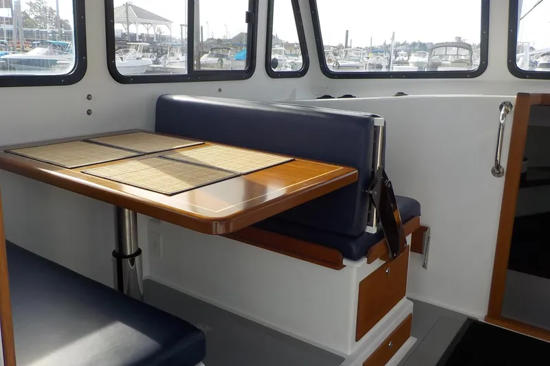 Slide: The Image of 2008 Calvin Beal Downeast boat interior with wooden table and blue seating. - 26