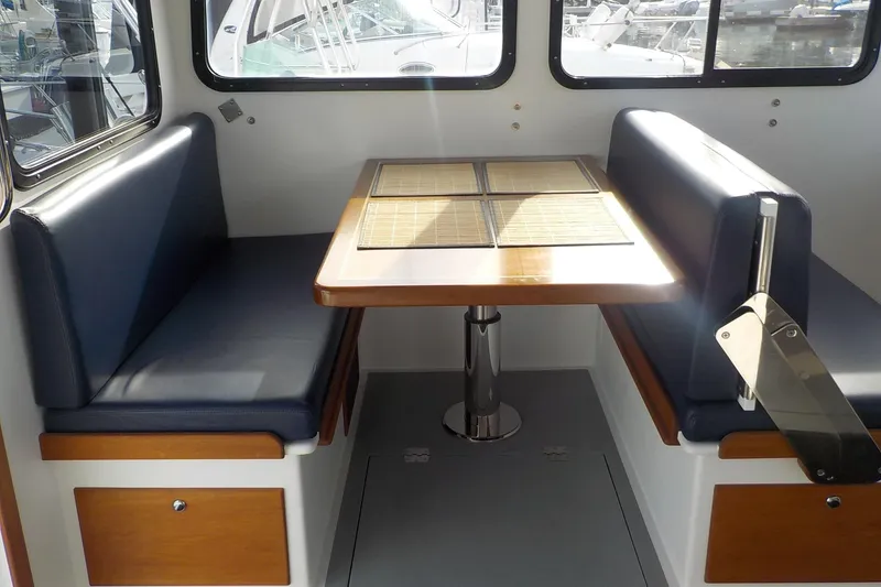 Slide: The Image of 2008 Calvin Beal Downeast boat interior with blue seating and wooden table. - 28