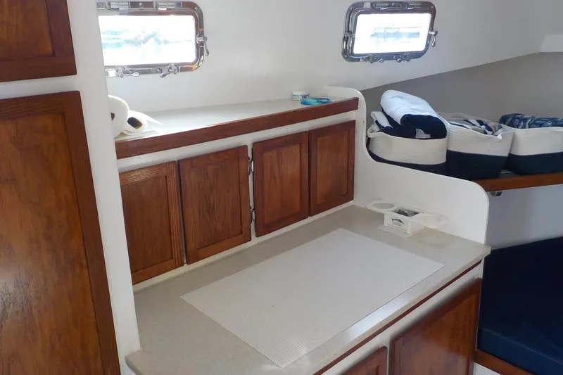 Slide: The Image of Interior of 2008 Calvin Beal Downeast boat with wooden cabinets and cozy seating area. - 32