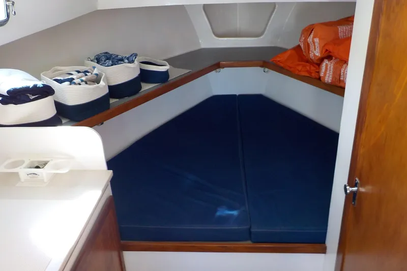 Slide: The Image of 2008 Calvin Beal Downeast boat cabin with blue cushions and storage baskets. - 34