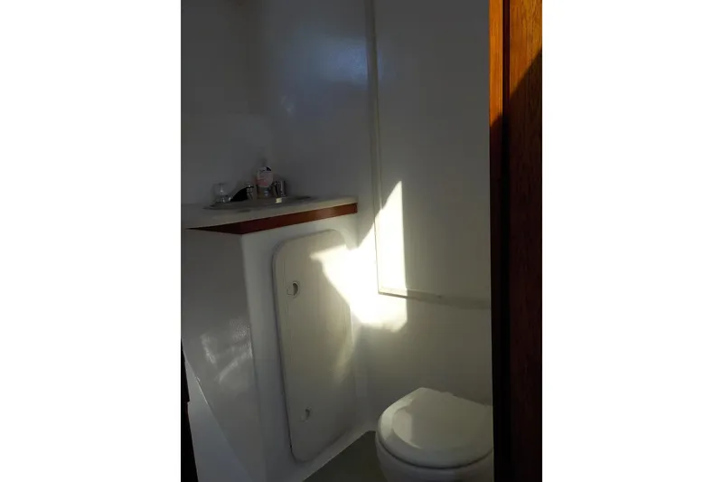 Slide: The Image of 2008 Calvin Beal Downeast boat bathroom with toilet and sink, illuminated by sunlight. - 36