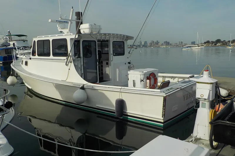 Slide: The Image of 2008 Calvin Beal Downeast boat docked in a marina with city skyline background. - 5