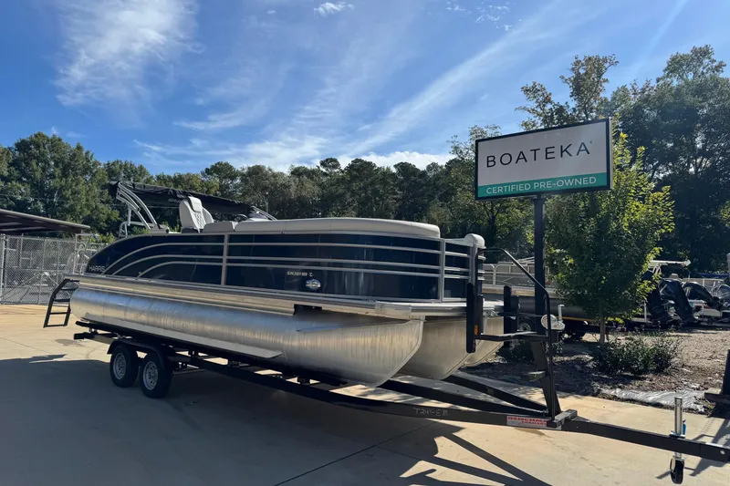 Slide: The Image of 2025 Harris Sunliner 230 pontoon boat on trailer at Boateka dealership. - 1