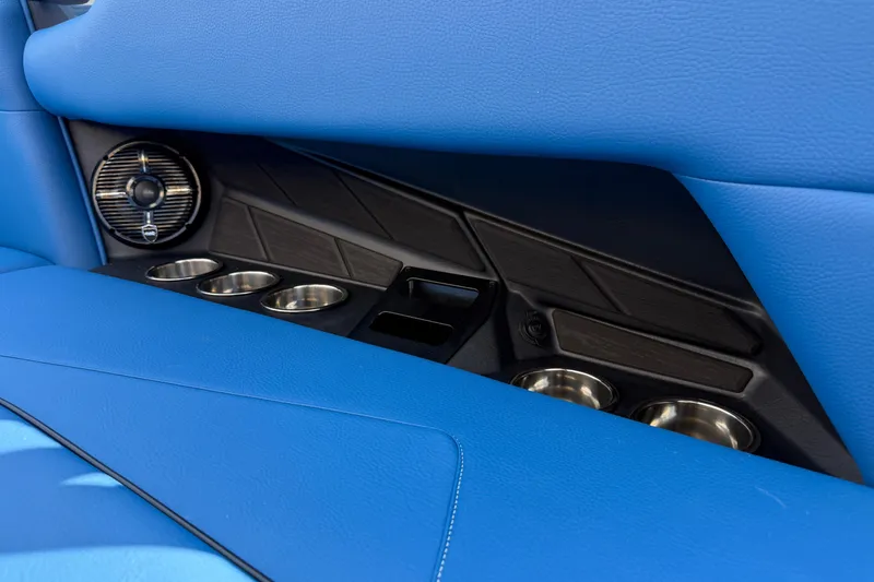 Slide: The Image of 2026 Moomba Tykon interior with blue upholstery, cup holders, and speaker detail. - 22