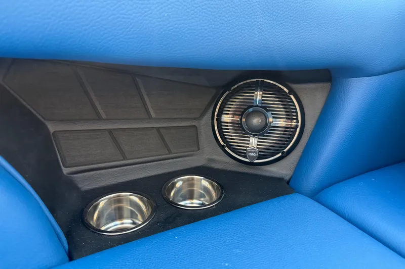 Slide: The Image of 2026 Moomba Tykon interior with blue upholstery, speaker, and dual cup holders. - 23