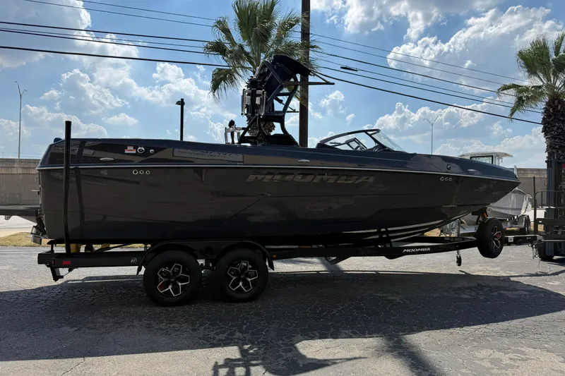 Slide: The Image of 2026 Moomba Tykon boat on trailer under a sunny sky with palm trees. - 6