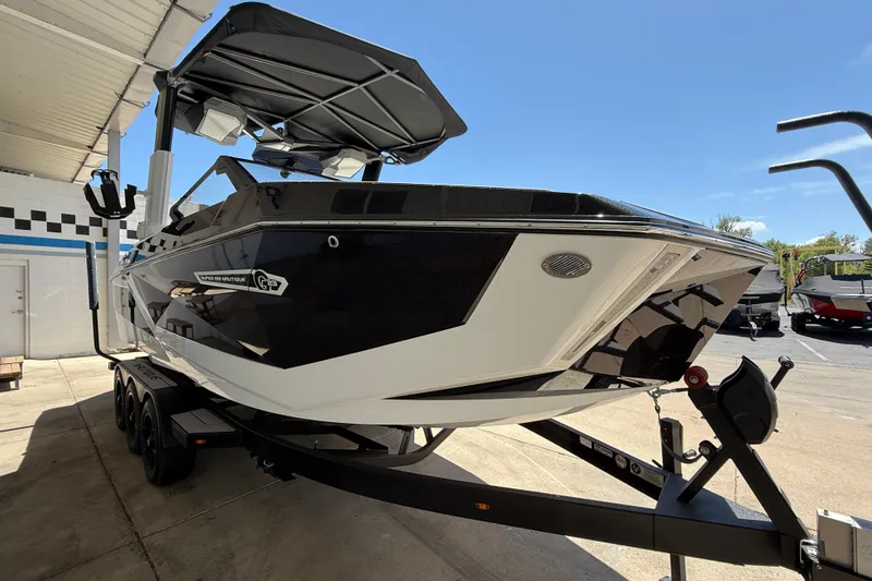 Slide: The Image of 2025 Nautique Super Air Nautique G23 boat on trailer, black and white design, parked outdoors. - 5