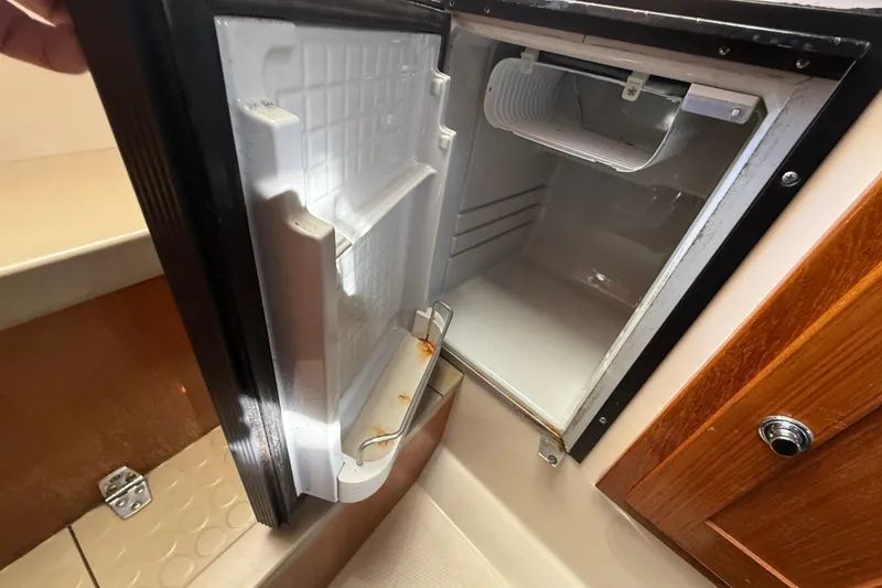 Slide: The Image of Open refrigerator inside 2005 Albemarle 280 Express Fisherman boat, showing interior storage space. - 45