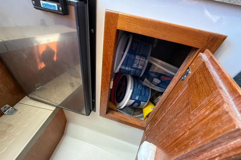 Slide: The Image of Open wooden cabinet on 2005 Albemarle 280 Express Fisherman, storing various containers. - 46