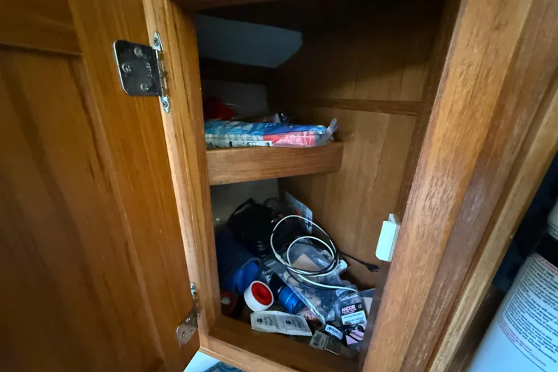 Slide: The Image of Wooden cabinet with assorted items inside, on a 2005 Albemarle 280 Express Fisherman boat. - 47