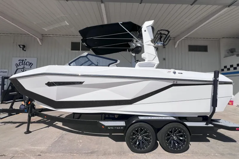 Slide: The Image of 2025 Nautique Super Air Nautique G21 boat on trailer, white with black accents, parked outdoors. - 1