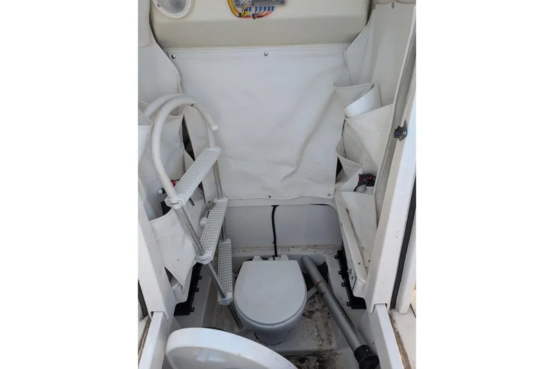 Slide: The Image of Interior of 2018 Wellcraft 242 Fisherman boat featuring compact marine toilet setup. - 5