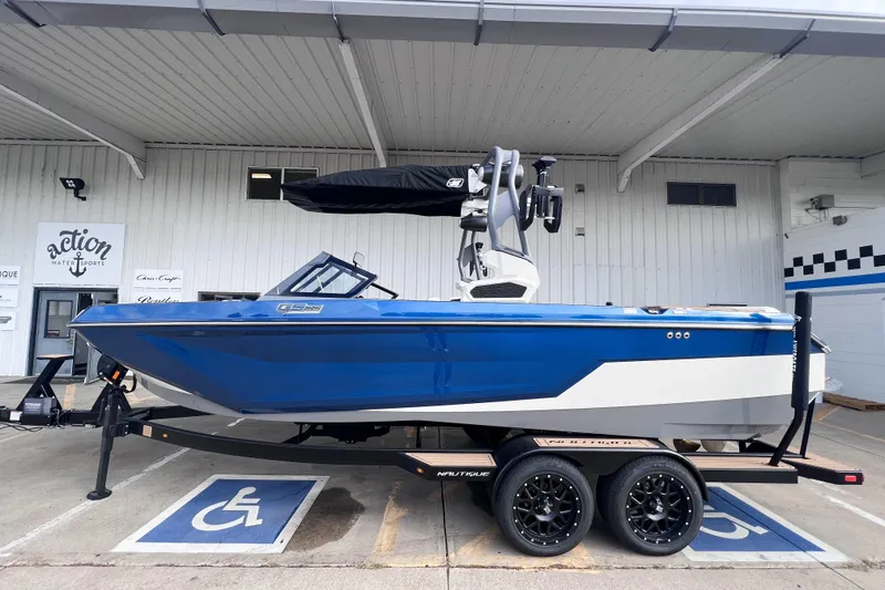 Slide: The Image of 2024 Nautique Super Air Nautique GS22 boat in blue, parked on a trailer. - 1