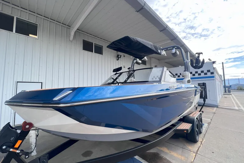 Slide: The Image of 2024 Nautique Super Air Nautique GS22 boat in blue, parked outside a building. - 3