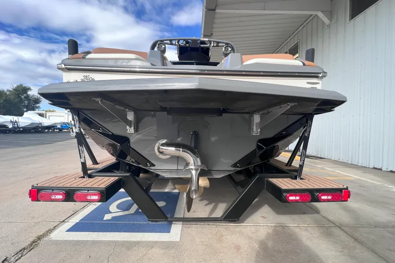 Slide: The Image of 2024 Nautique Super Air Nautique GS22 boat rear view at a marina. - 5