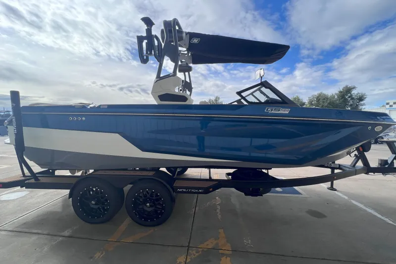 Slide: The Image of 2024 Nautique Super Air Nautique GS22 boat on trailer, blue and white design. - 8
