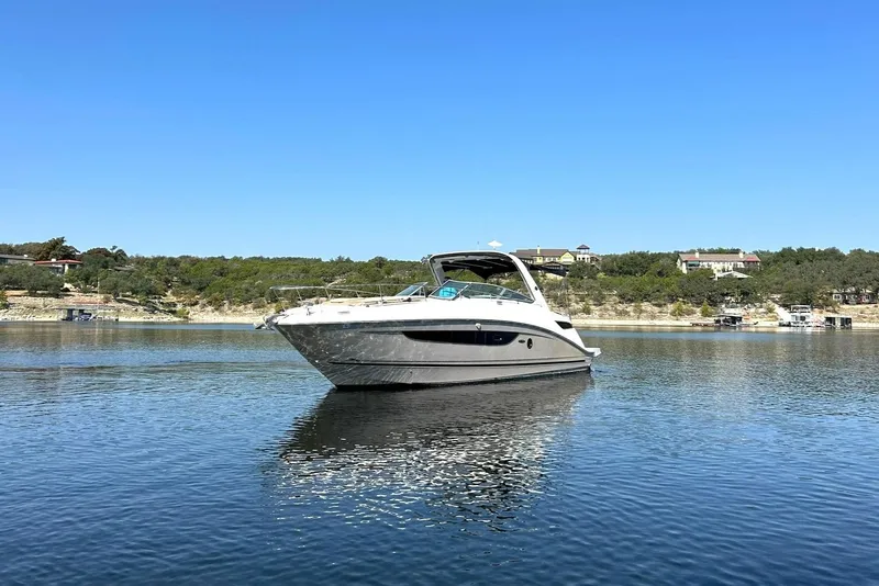 Slide: The Image of 2014 Sea Ray 350 Sundancer yacht on calm water with scenic shoreline background. - 11