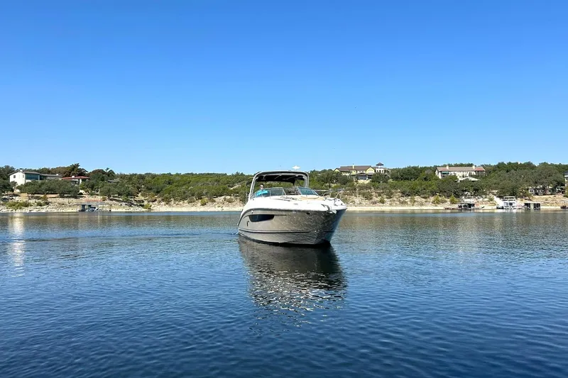 Slide: The Image of 2014 Sea Ray 350 Sundancer yacht on calm water with scenic shoreline background. - 14