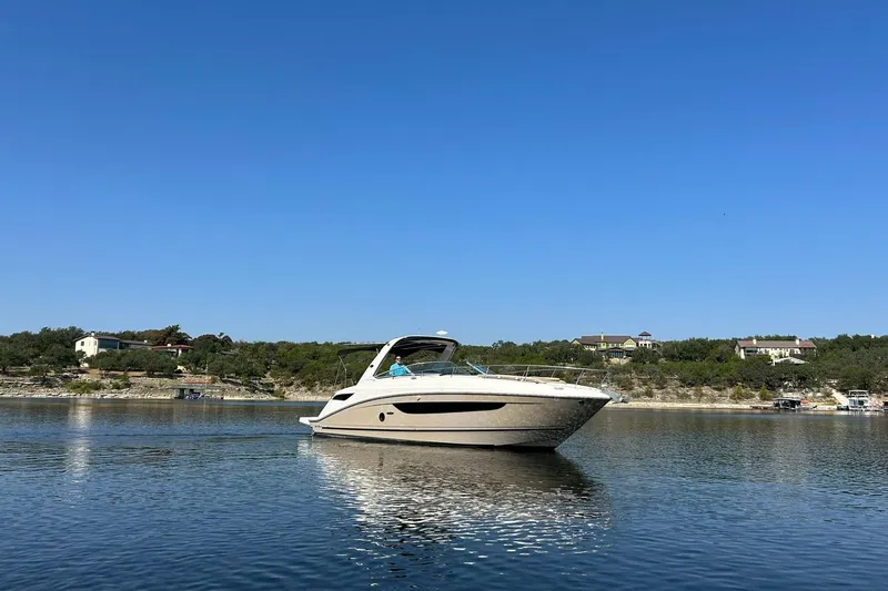 Slide: The Image of 2014 Sea Ray 350 Sundancer cruising on a calm lake under a clear blue sky. - 16