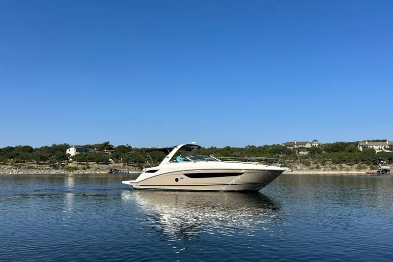 Slide: The Image of 2014 Sea Ray 350 Sundancer cruising on a calm lake under a clear blue sky. - 17