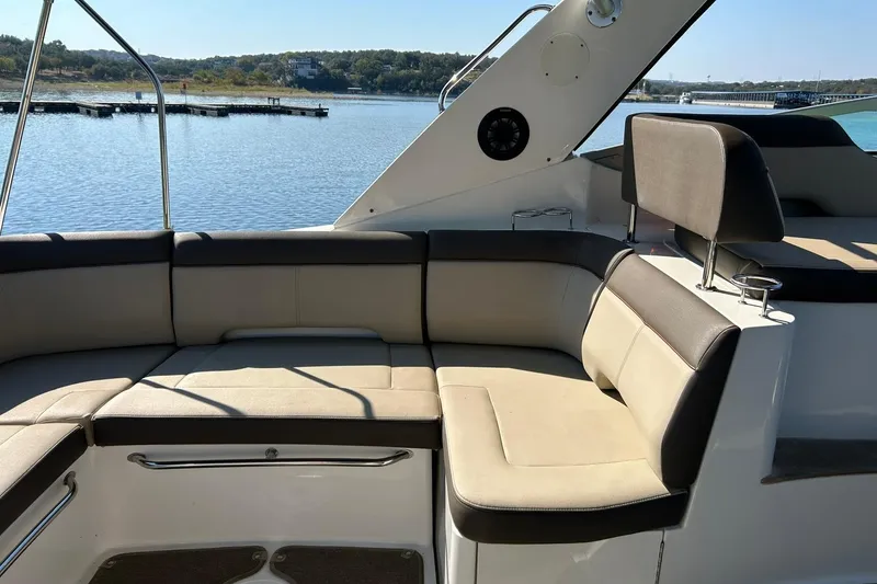 Slide: The Image of 2014 Sea Ray 350 Sundancer boat interior with beige seating, overlooking a serene lake. - 32