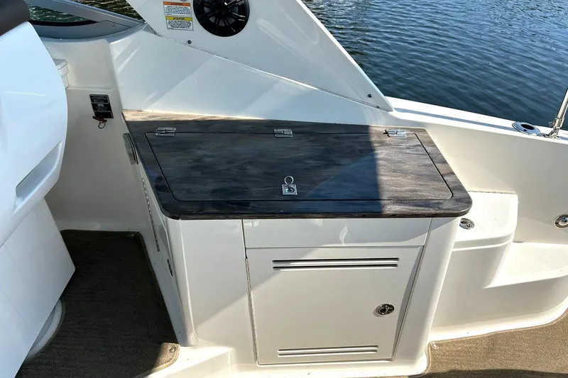 Slide: The Image of 2014 Sea Ray 350 Sundancer boat interior with wooden countertop and storage cabinet. - 36