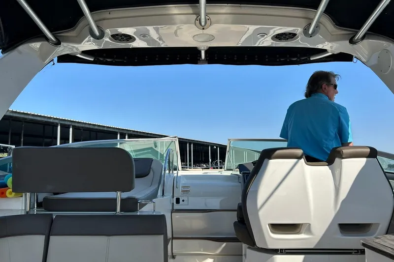 Slide: The Image of 2014 Sea Ray 350 Sundancer interior with person at helm, marina background. - 43