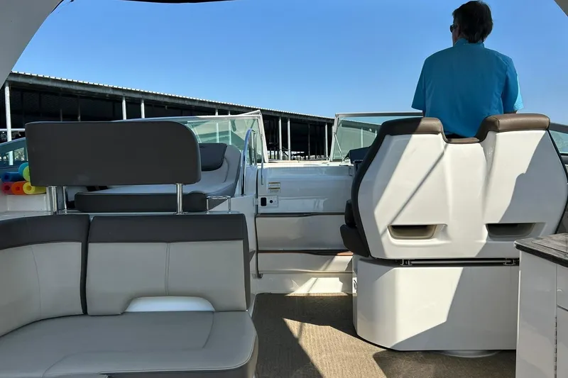 Slide: The Image of 2014 Sea Ray 350 Sundancer interior with seating and helm, featuring a person in blue shirt. - 44