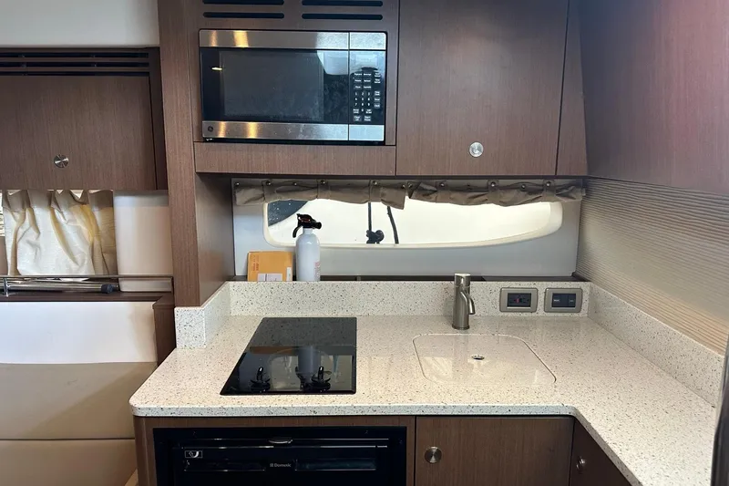 Slide: The Image of 2014 Sea Ray 350 Sundancer kitchen with microwave, stove, and sink. - 59