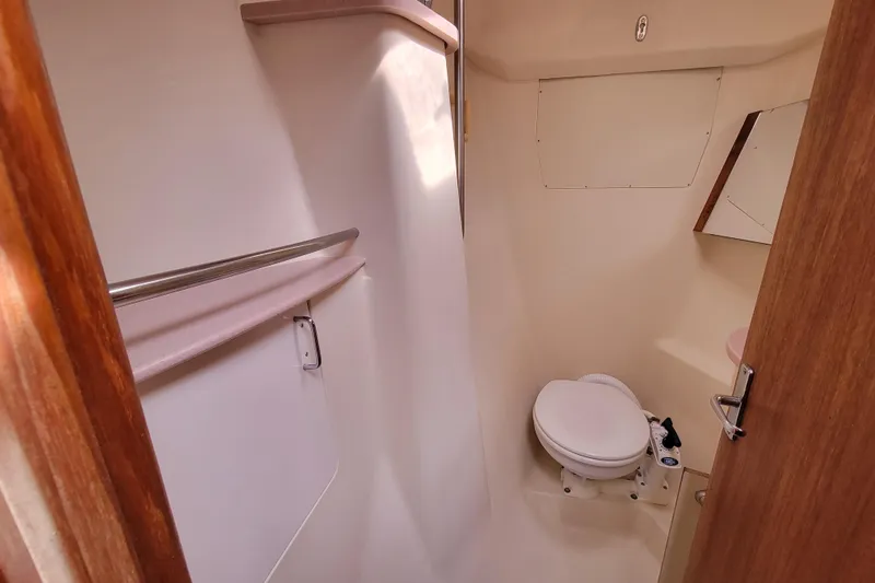 Slide: The Image of 2001 Hunter Passage 420 yacht bathroom with toilet, mirror, and wooden door. - 33